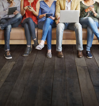 people sitting on a couch holding various electronic devices